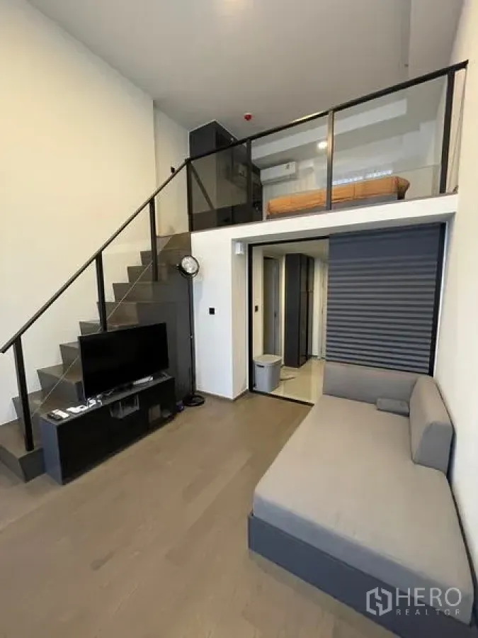 公寓 出租在Bang Rak, Bangkok - 客厅设沙发与电视，夹层上方为玻璃栏杆。