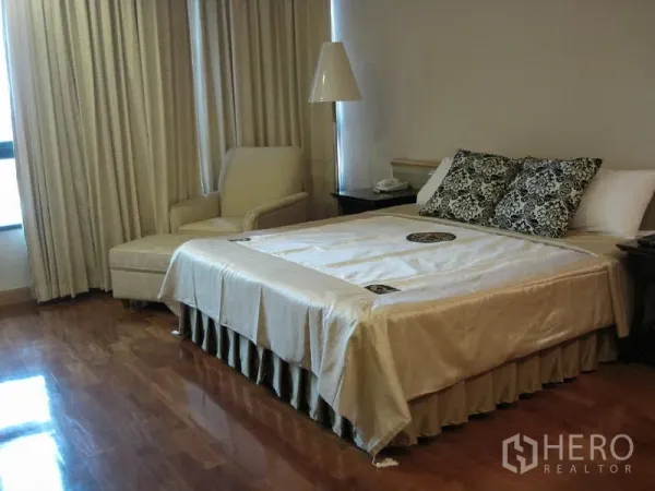 公寓 出租在Pathum Wan, Bangkok - 卧室配有特大床、躺椅与落地窗帘，抛光木地板温馨大方。