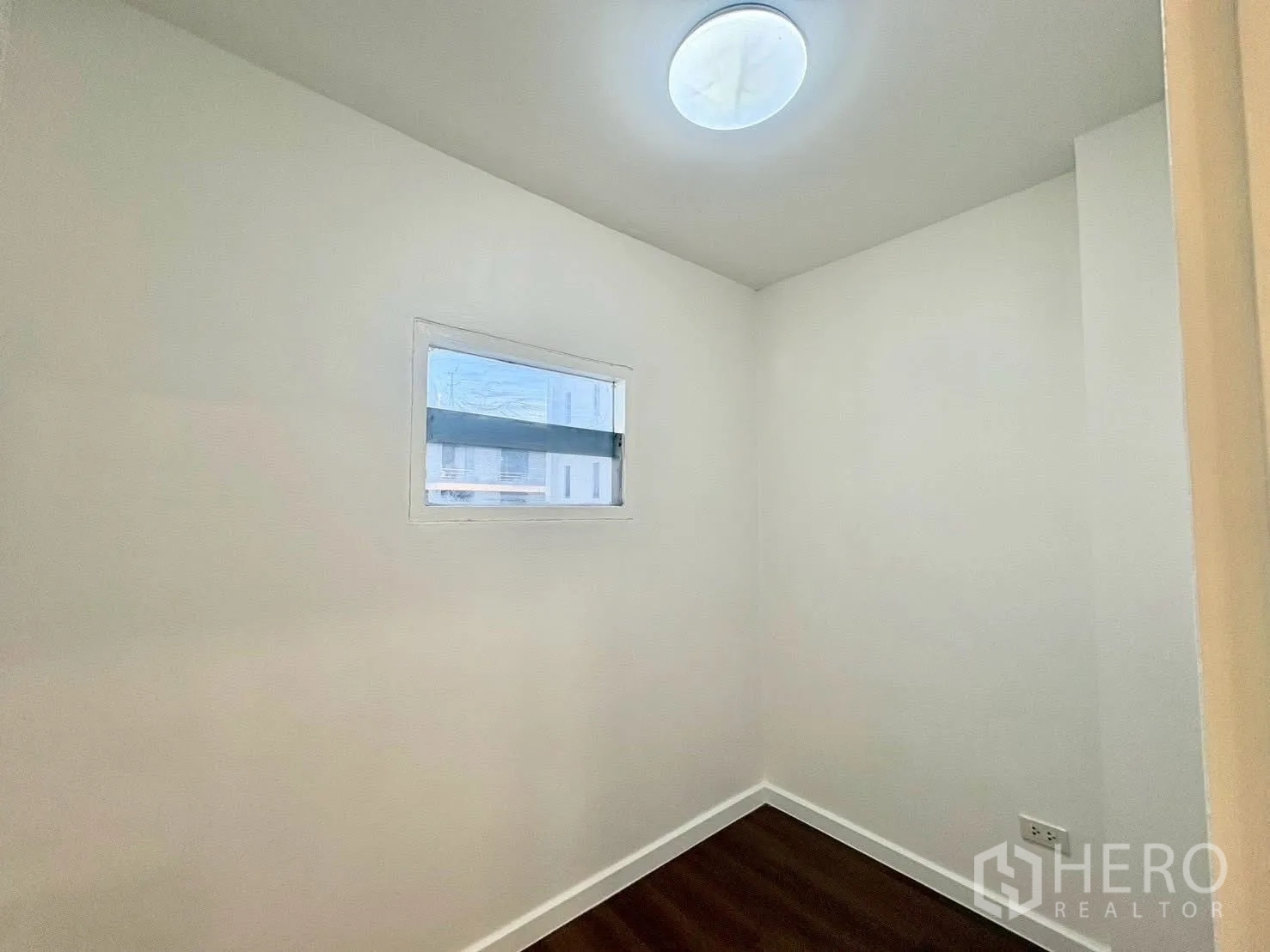 联排别墅 for rent in Huai Khwang, Bangkok - 小巧房间，白墙木地板与窄窗。