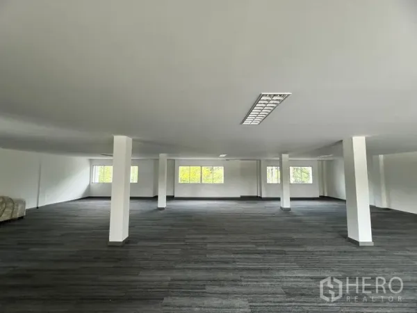 零售空间 出租在Huai Khwang, Bangkok - 开放式零售楼层，白色立柱、地毯地面与吊顶灯具，多扇窗户带来自然采光。