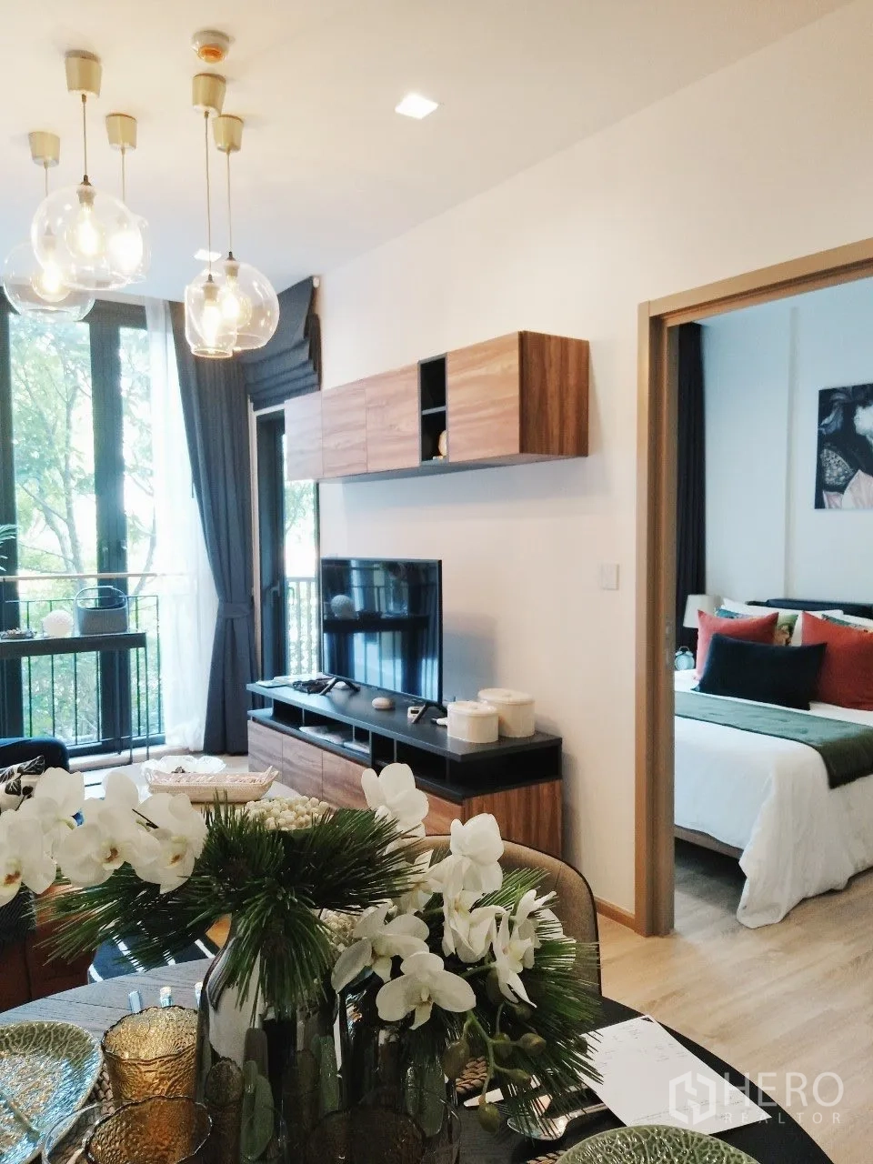 公寓 for rent in Watthana, Bangkok - 开放式客厅，吊灯、电视柜与通往卧室的门口。