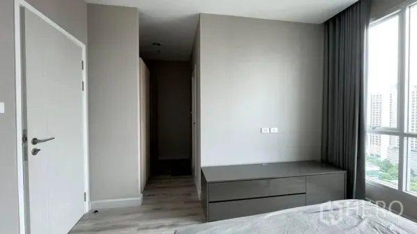 公寓 出售在Sathon, Bangkok - 极简卧室一角，内置抽屉柜、白色门与落地窗采光。