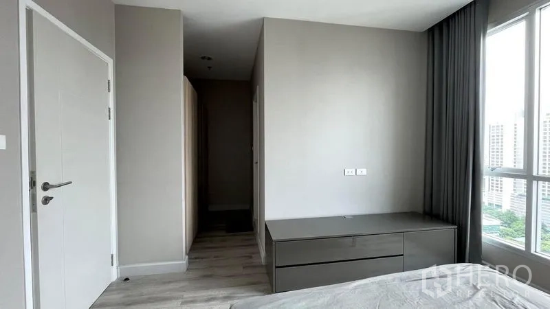 公寓 出售在Sathon, Bangkok - 极简卧室一角，内置抽屉柜、白色门与落地窗采光。