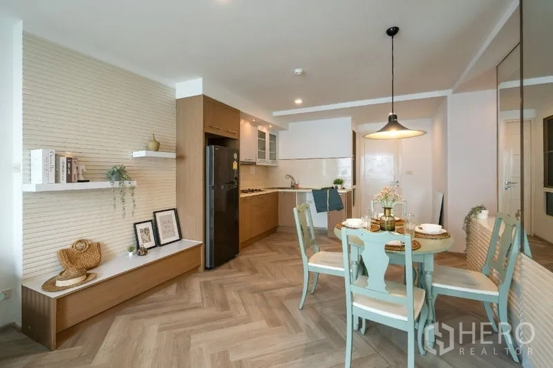 Condominium for sale in Watthana, Bangkok - Open-plan kitchen and dining area with wood cabinetry, herringbone floors and a pendant light.