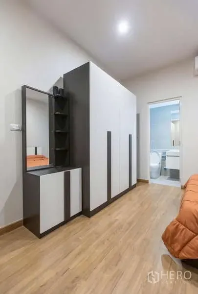 独立式住宅 出租或出售在Lat Phrao, Bangkok - 卧室过道设大衣柜与梳妆台，并有门通往套内卫浴。