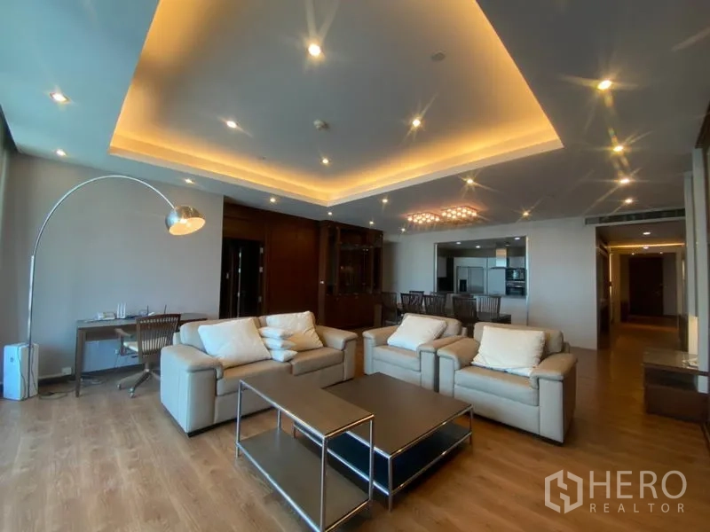 公寓 出租在Sathon, Bangkok - 宽敞客厅，皮质沙发、吊顶氛围灯、木地板与内置柜。