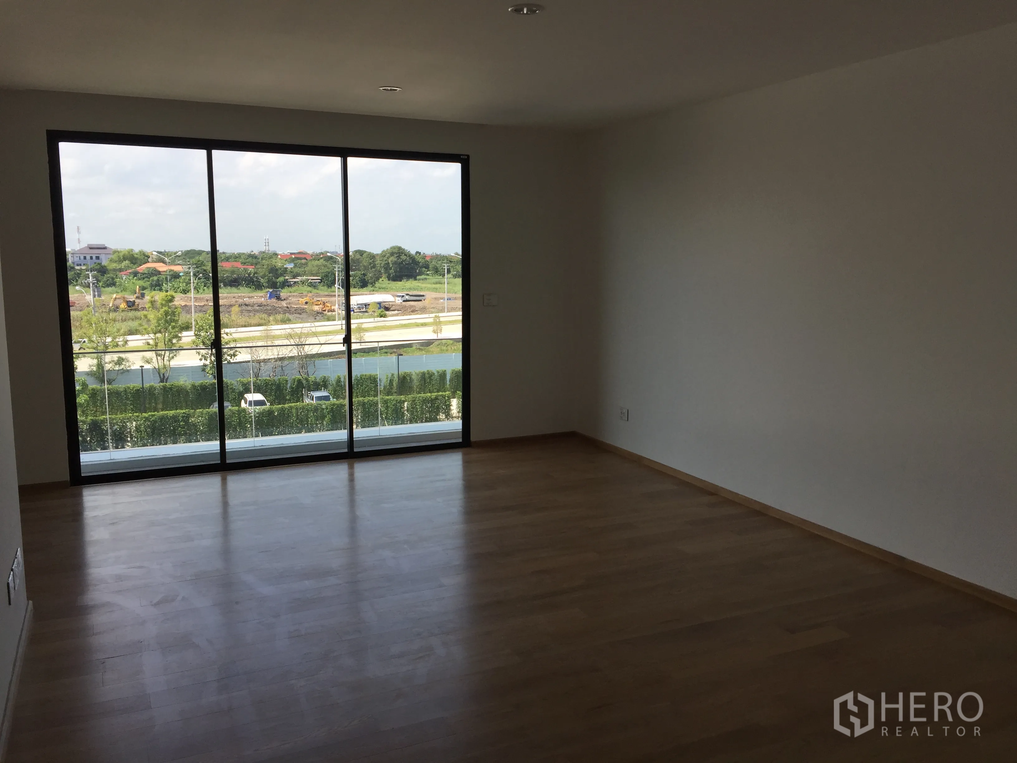 Townhouse for rent in Saphan Sung, Bangkok - Large room with floor-to-ceiling sliding glass doors opening to green views.