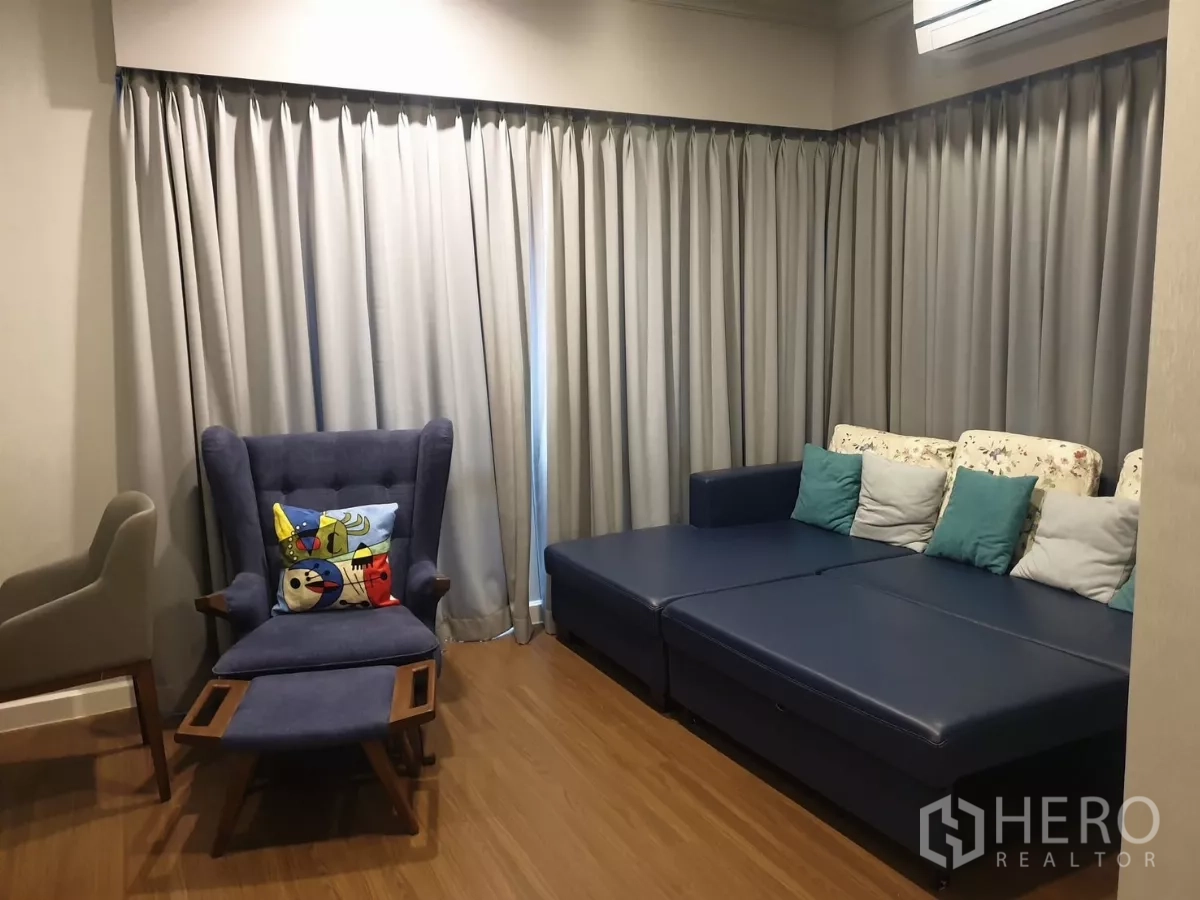 บ้าน ให้เช่าหรือขายในPrawet, Bangkok - ห้องนั่งเล่นชั้นบน โซฟาสีน้ำเงิน เก้าอี้วิงแบ็ก และผ้าม่านทึบยาว