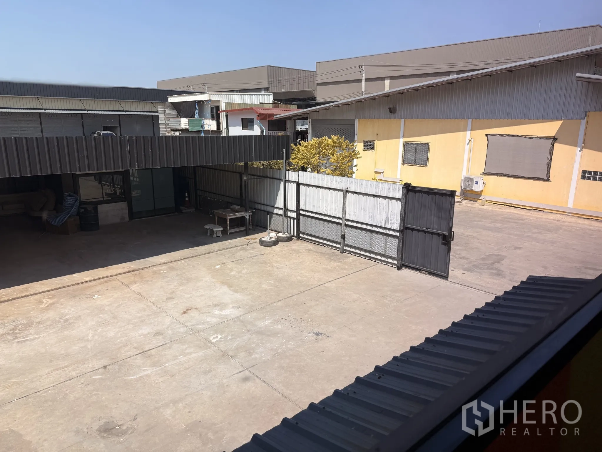 คลังสินค้า for rent in Lat Krabang, Bangkok - ภาพจากชั้นบนเห็นลานคอนกรีตกว้างและประตูรั้วบานเลื่อนของพื้นที่โกดัง