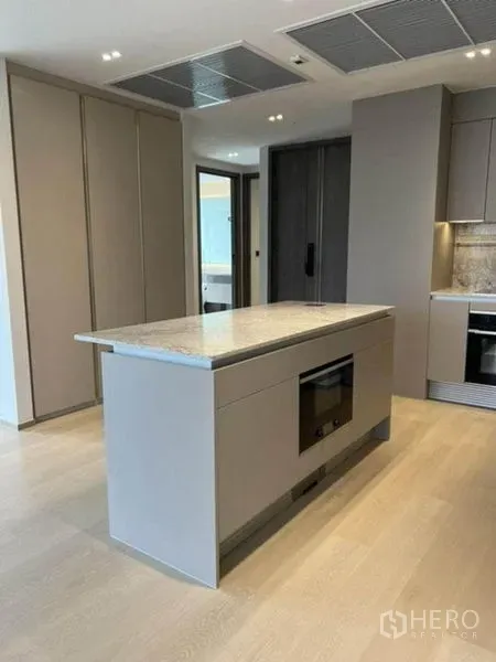 Condominium for rent in Pathum Wan, Bangkok - Kitchen island with built-in oven and ceiling vents, ample storage.