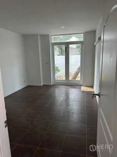 Home Office for sale - Ground-floor bedroom or office with dark tiles and a tall glass door opening to the garden.