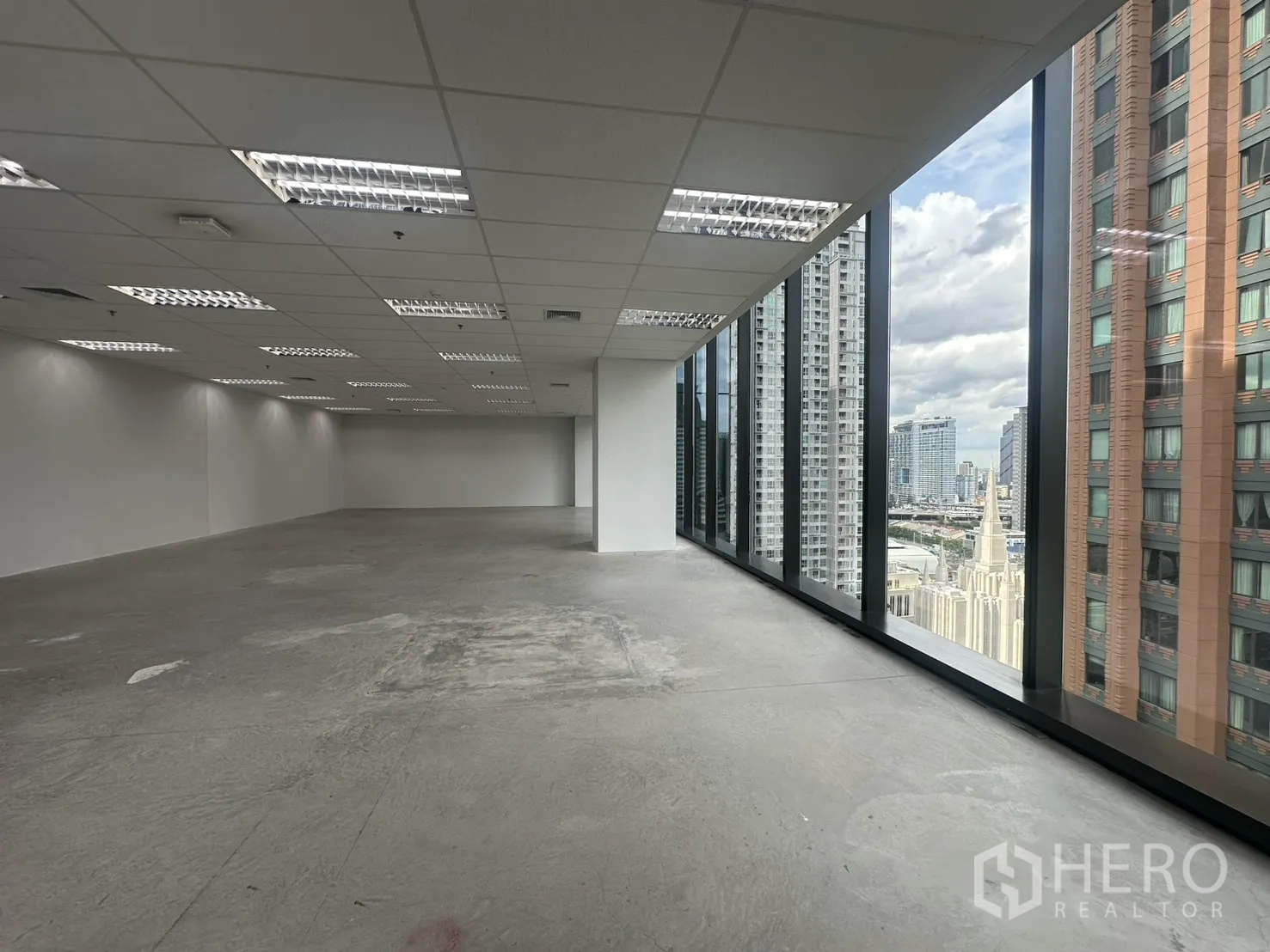 Office Space for rent in Ratchathewi, Bangkok - Large unfurnished office floor with drop ceiling lights and full-height glass facade.