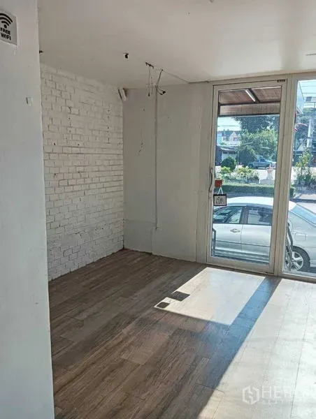 店屋 出租在Wang Thonglang, Bangkok - 旺通朗明亮店铺空间，白色砖墙、木纹地板与整面玻璃门头。