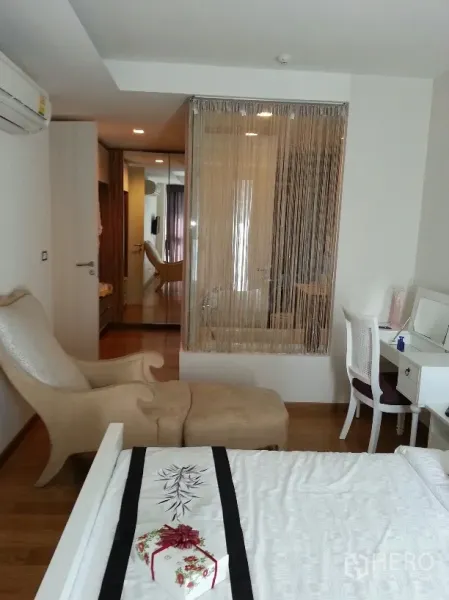 คอนโด ให้เช่าในWatthana, Bangkok - มุมห้องนอนหลักพร้อมเก้าอี้เอน โต๊ะเครื่องแป้ง และผนังกระจกกั้นอ่างอาบน้ำ