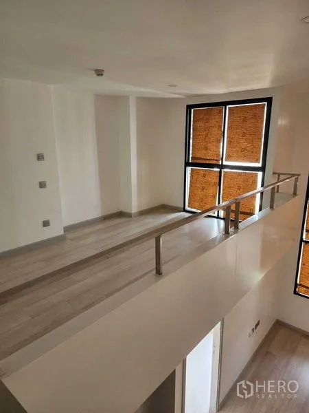 คอนโด ขายในSathon, Bangkok - ทางเดินชั้นลอยพร้อมราวสแตนเลส มองลงสู่พื้นที่นั่งเล่นและหน้าต่างสูง