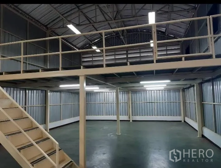 Warehouse for rent in Bang Kho Laem, Bangkok - Ground floor area beneath the mezzanine with columns and bright fluorescent lights.