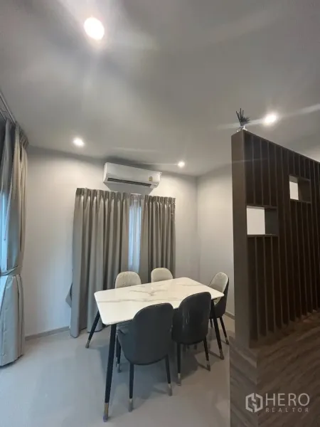 Detached House for rent in Khlong Sam Wa, Bangkok - Cozy dining nook with marble-top table, air-conditioning and curtains.