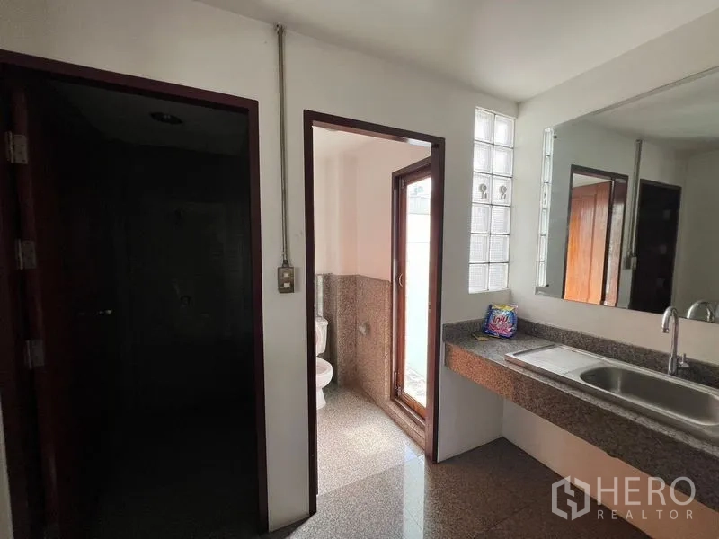 Office Space for rent in Watthana, Bangkok - Restroom with long granite vanity, mirror, and a separate toilet room.
