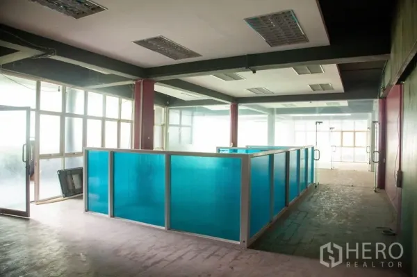 货栈 出租在Prawet, Bangkok - 开放式工作区，蓝色隔断、荧光灯和磨砂窗，位于帕威区仓库内。