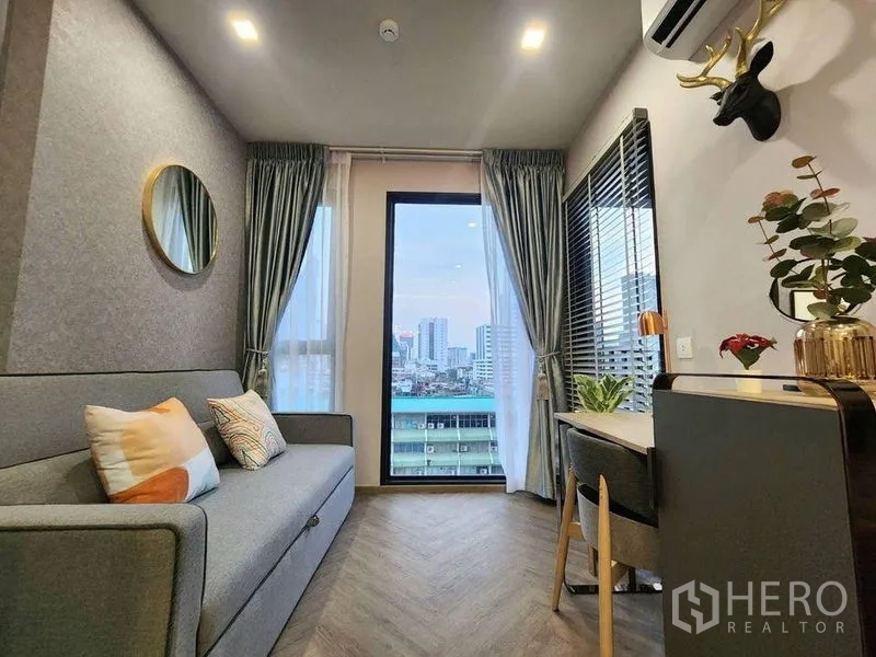Condominium for rent in Bang Rak, Bangkok - Second bedroom or study with sofa, desk and floor-to-ceiling window overlooking the skyline.