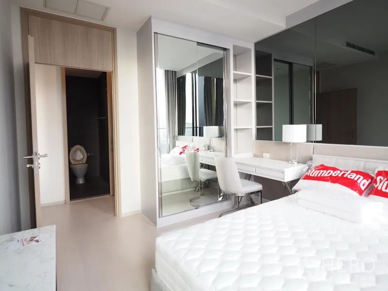 Condominium for rent in Pathum Wan, Bangkok - Second bedroom with built-in mirrored wardrobe, study desk and en-suite toilet entrance.