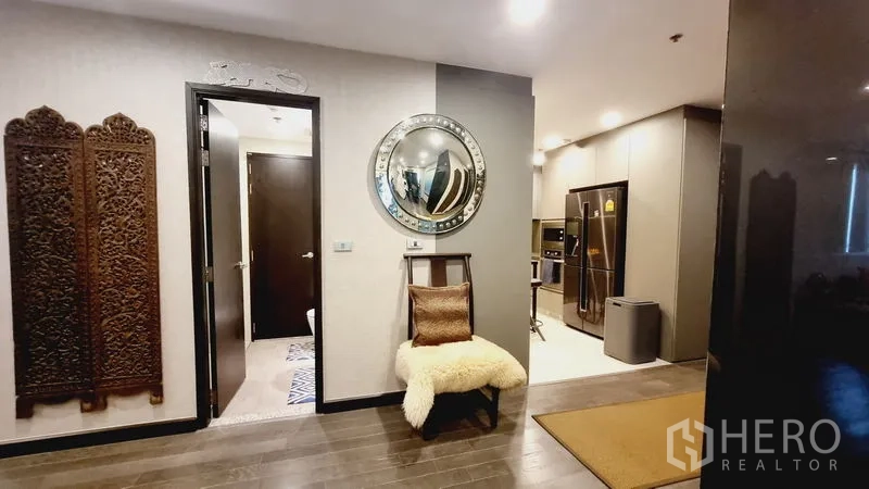 公寓 出售在Watthana, Bangkok - 过道一隅设圆形镜与单椅，可见现代厨房一角。