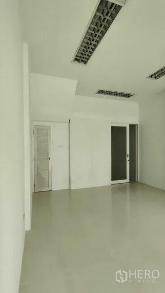 Townhouse for sale in Bang Khen, Bangkok - Clean white room with tiled floor, recessed fluorescent lights, and a sliding door.