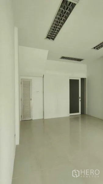 Townhouse for sale in Bang Khen, Bangkok - Clean white room with tiled floor, recessed fluorescent lights, and a sliding door.
