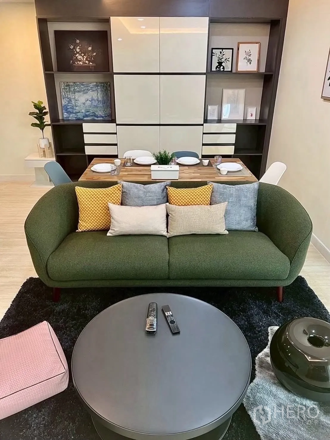 Condominium for rent in Huai Khwang, Bangkok - Living room featuring green sofa, cushions, and built-in shelving.