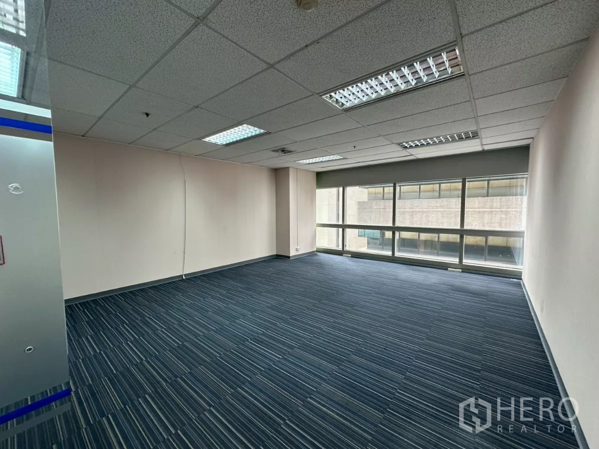 Office Space for rent in Watthana, Bangkok - Office with glass entry, blue carpet and wide window facing an adjacent building.