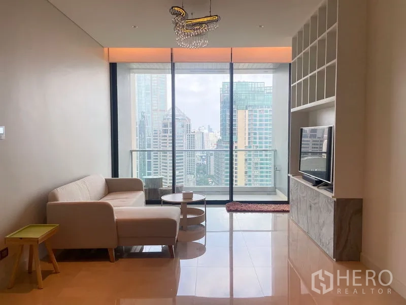 คอนโด ให้เช่าในPathum Wan, Bangkok - ห้องนั่งเล่นสว่างพร้อมกระจกเต็มผนัง ระเบียง และวิวสกายไลน์ใจกลางกรุงเทพฯ