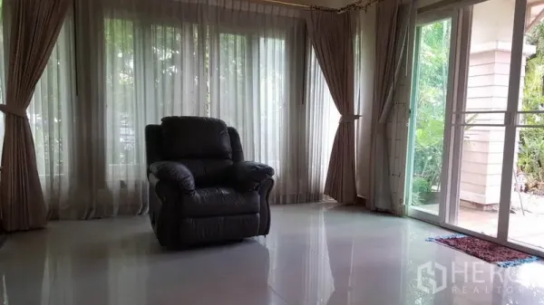 บ้าน ขายในMueang Nonthaburi, Nonthaburi - ห้องนั่งเล่นสว่าง มีผ้าม่านยาวแตะพื้น ประตูกระจกบานเลื่อน และเก้าอี้เอนหนัง