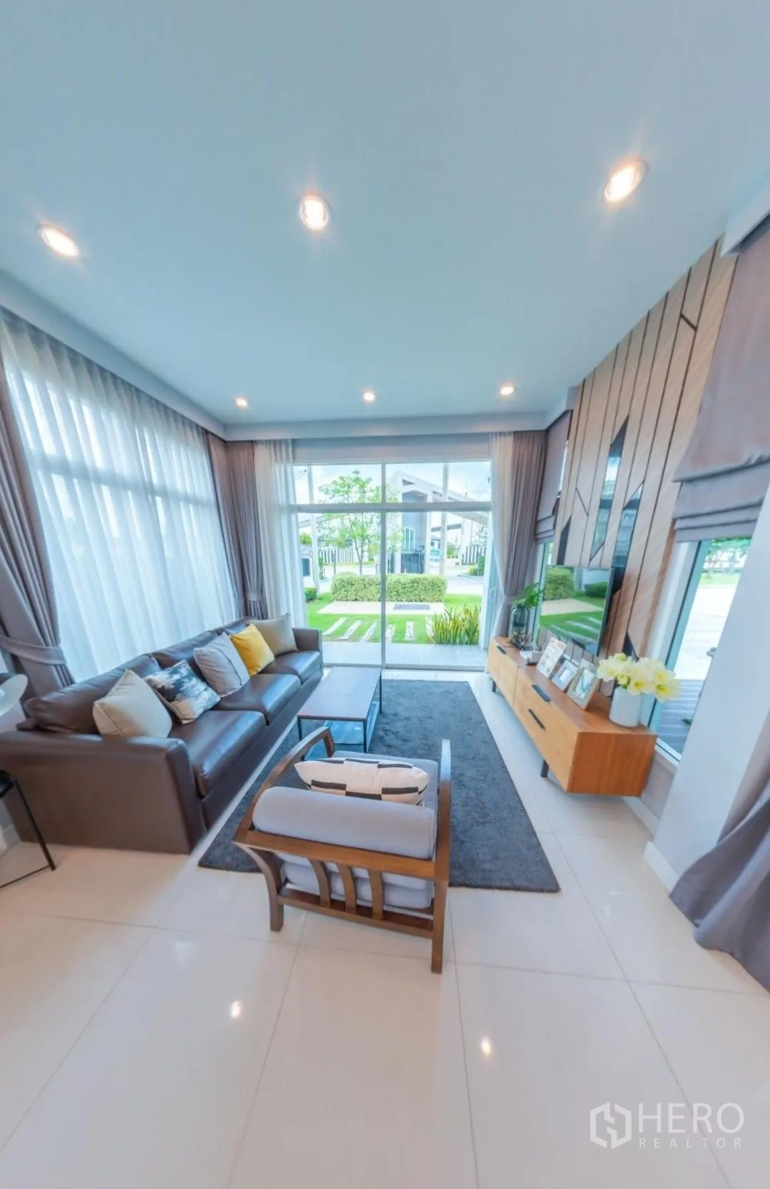 独栋房屋 for rent in Lam Luk Ka, Pathum Thani - 现代客厅，落地大窗、沙发组合、电视柜，外接花园景观。