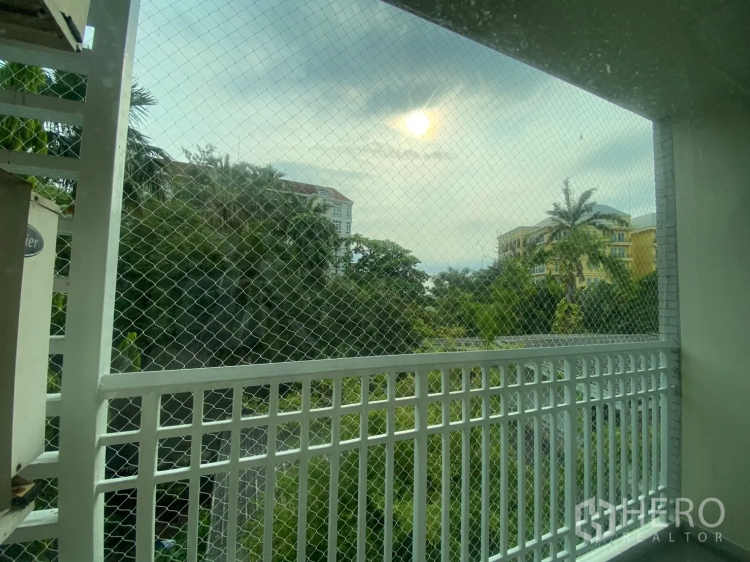 Condominium for rent or sale in Sathon, Bangkok - Balcony with safety net overlooking trees and nearby low-rise buildings.