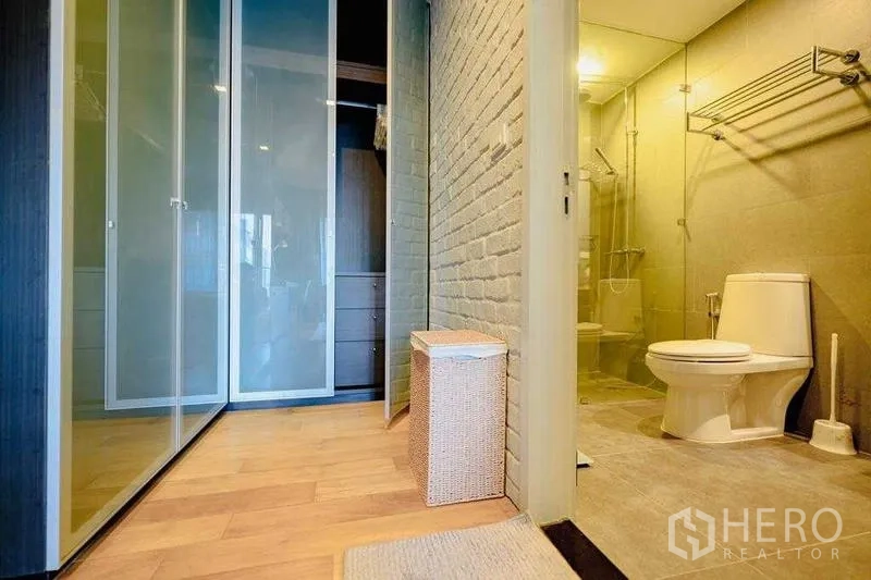 Condominium for rent in Watthana, Bangkok - Walk‑in closet with frosted sliding doors next to bathroom with glass shower.