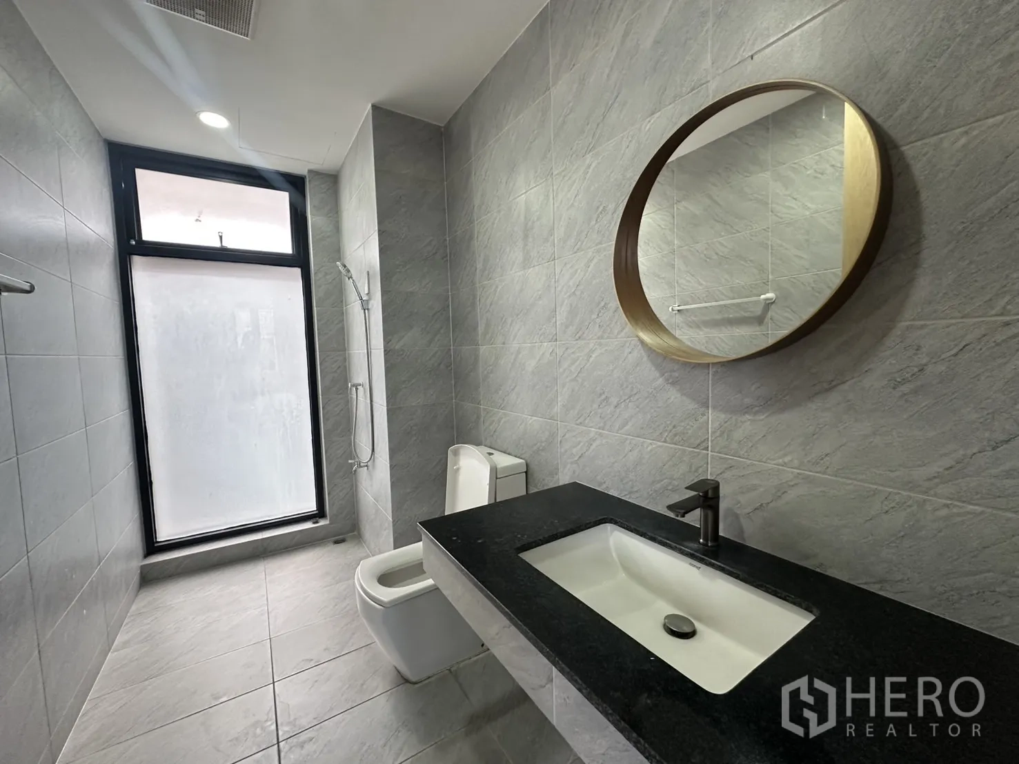 带办公室的家 出租在Pathum Wan, Bangkok - 灰砖卫生间，圆镜、台盆与马桶，旁有磨砂窗