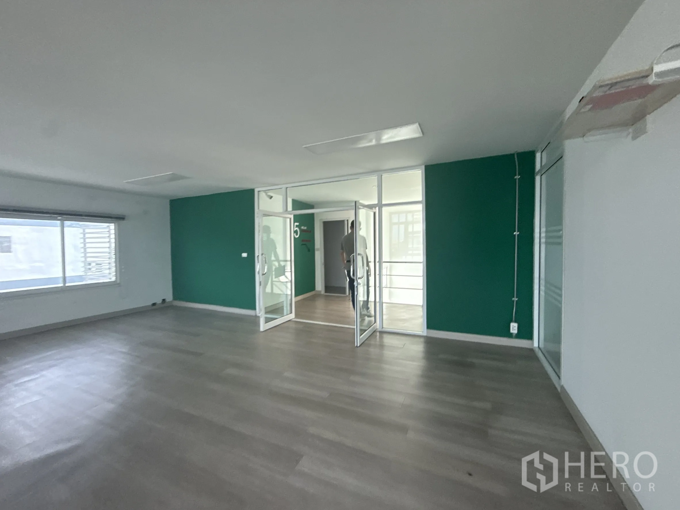 สำนักงาน ให้เช่าในBueng Kum, Bangkok - ห้องสำนักงานโล่ง พื้นไม้ ผนังสีเขียว และประตูกระจกบานคู่