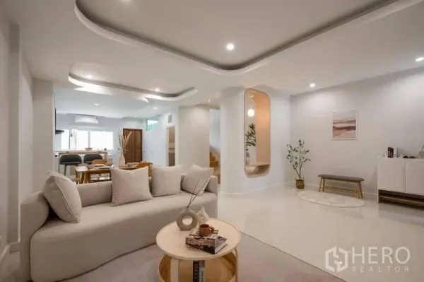 联排别墅 出售在Khlong Toei, Bangkok - 开放式客餐厅，曲线吊顶、柔和灯光与米色沙发，后接餐区。