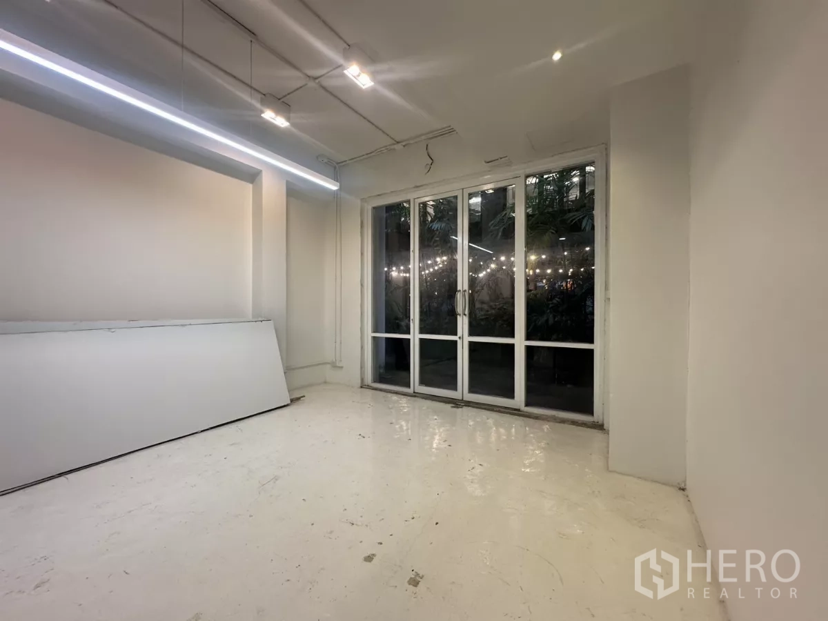 带办公室的家 出租在Pathum Wan, Bangkok - 明亮工作区，长条LED灯与落地玻璃门，对景绿植。