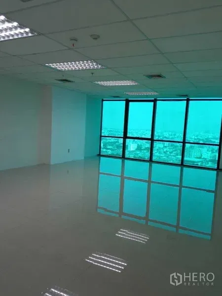 Office Space for rent in Huai Khwang, Bangkok - Spacious work area with turquoise-tinted panoramic windows overlooking the city skyline.