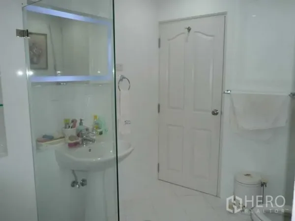 Detached House for rent in Bang Kapi, Bangkok - Bright white bathroom with glass shower enclosure and pedestal sink.