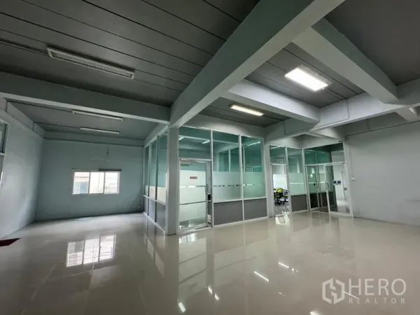 Warehouse for rent or sale in Chon Buri - Spacious office floor inside the warehouse with glossy tiles and glass-partitioned rooms under bright lights.