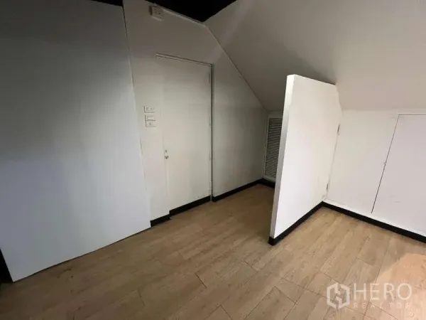 零售空间 出租在Watthana, Bangkok - 小型后室，斜顶白墙，百叶门与木纹复合地板。