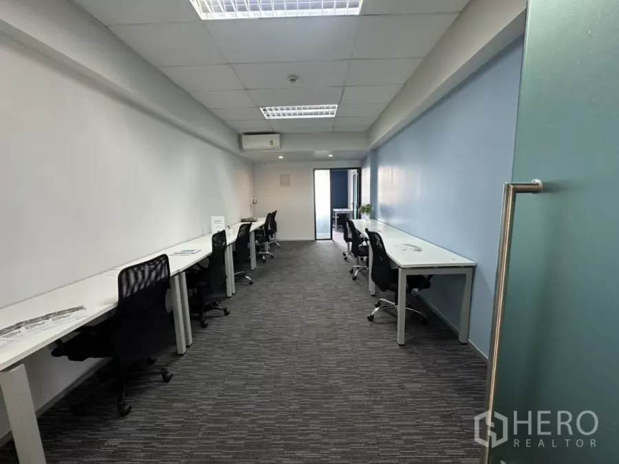 办公空间 出租在Watthana, Bangkok - 长形精装办公室，白色书桌与黑色座椅，地毯地面，尽头为玻璃门，位于通罗。