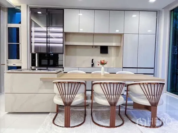Detached House for rent in Bueng Kum, Bangkok - Bright modern kitchen with island, built-in cabinetry and dining set beside floor-to-ceiling windows.