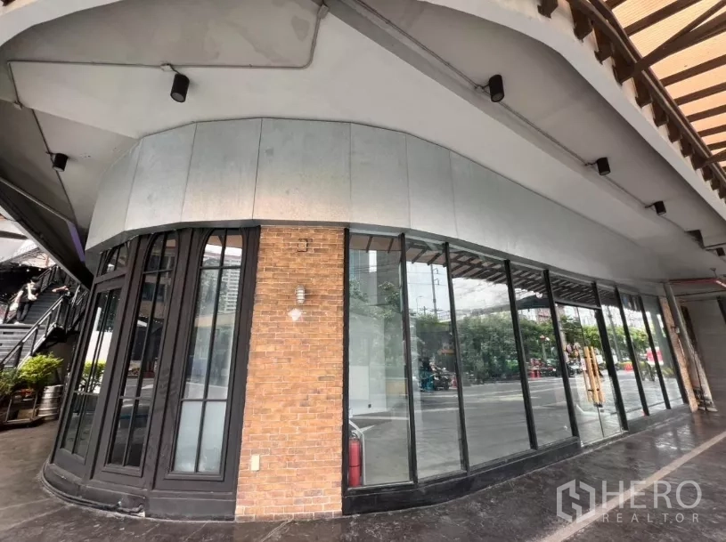 พื้นที่ขายปลีก ให้เช่า - ด้านหน้าโค้งมุมมีเสาอิฐและกระจกสูงรอบด้าน เหมาะสำหรับป้ายและการโชว์แบรนด์.