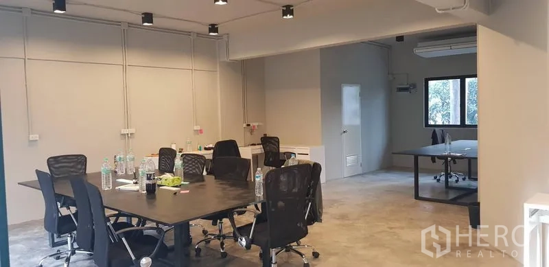 Office Space for rent in Khlong Toei, Bangkok - Wide view of modern workspace with track lighting, multiple desks and an adjoining room with window and AC.