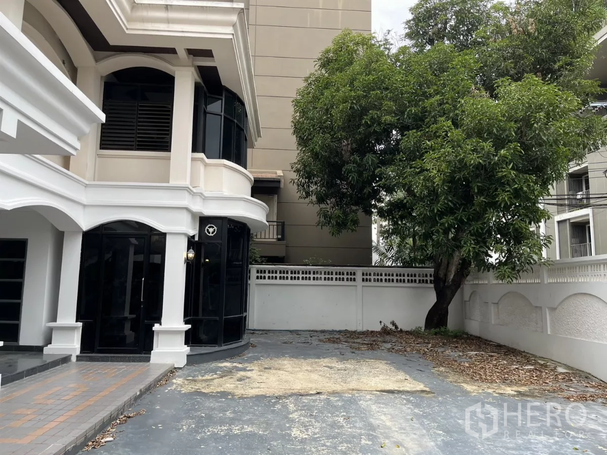 บ้าน ให้เช่าในWatthana, Bangkok - มุมภายนอกด้านข้าง โชว์กระจกมุมอาคาร ลานจอดรถกว้าง และต้นไม้ใหญ่ให้ร่มเงา.