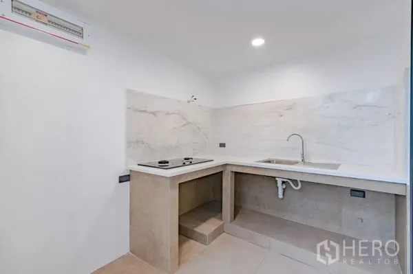 Townhouse for sale - Compact corner kitchen with stone countertops, sink, and electric cooktop.