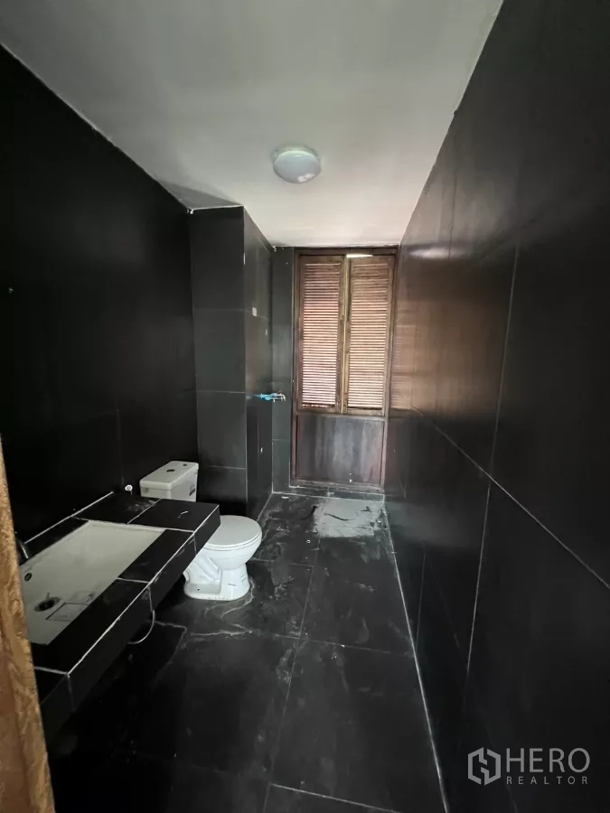 零售空间 出租在Khlong Toei, Bangkok - 狭长黑砖卫生间，配马桶与洗手盆。